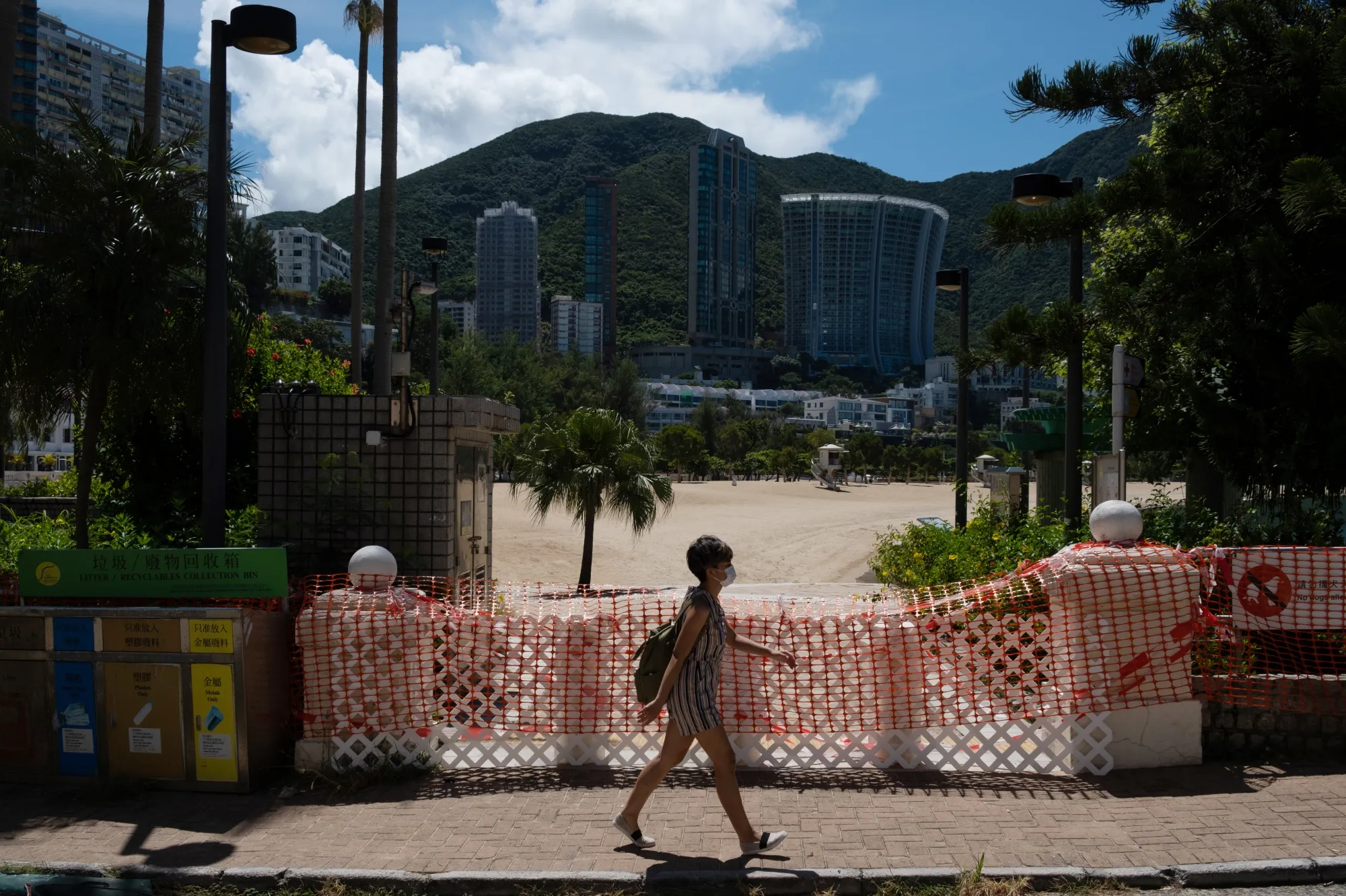 A pedestrian wearing a protective mask walks past a closed Repulse Bay beach in Hong Kong.