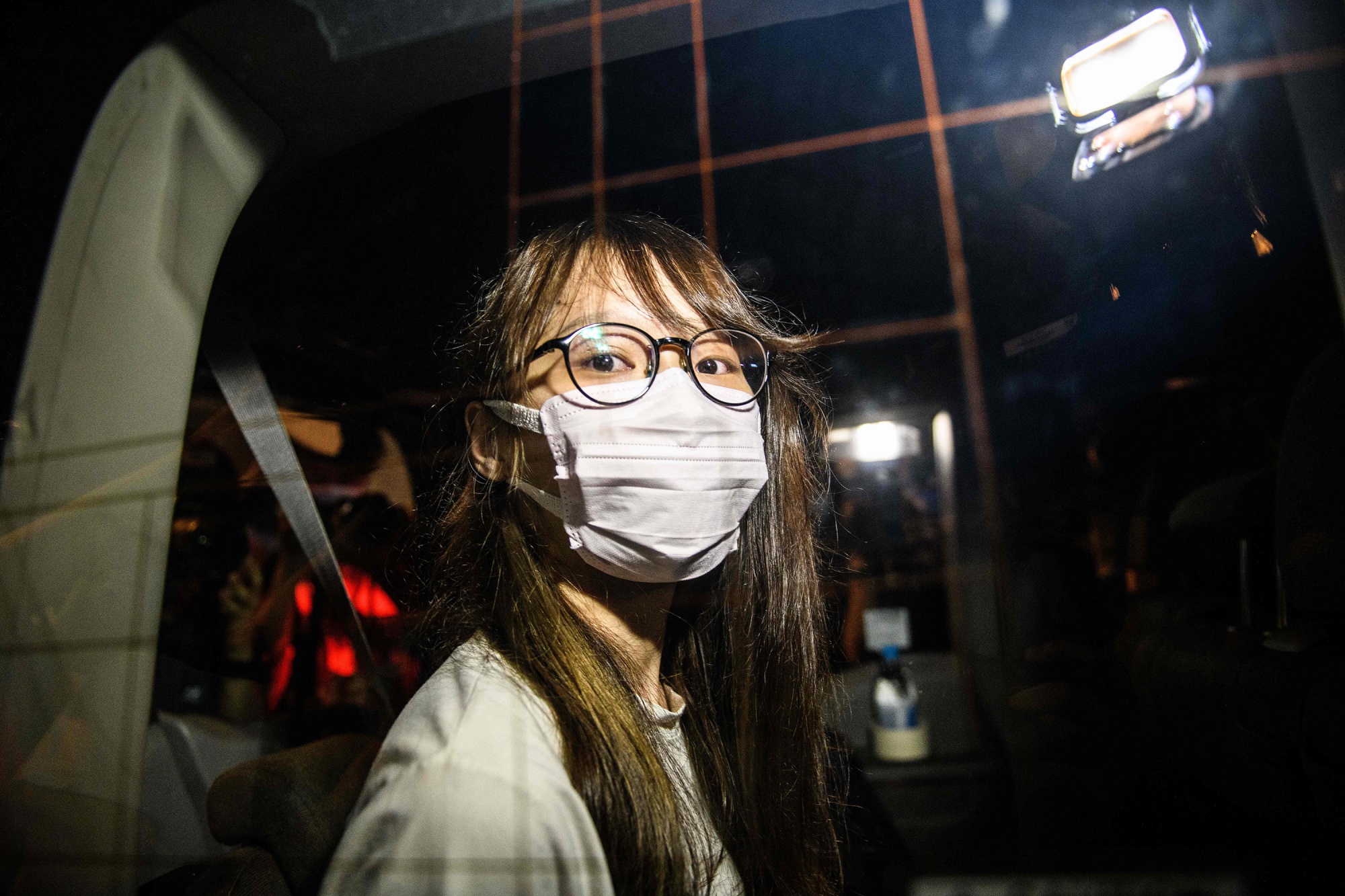 Agnes Chow looks out of a car window while being driven away by police from her home following arrest&nbsp;in Hong Kong, on Aug. 10.