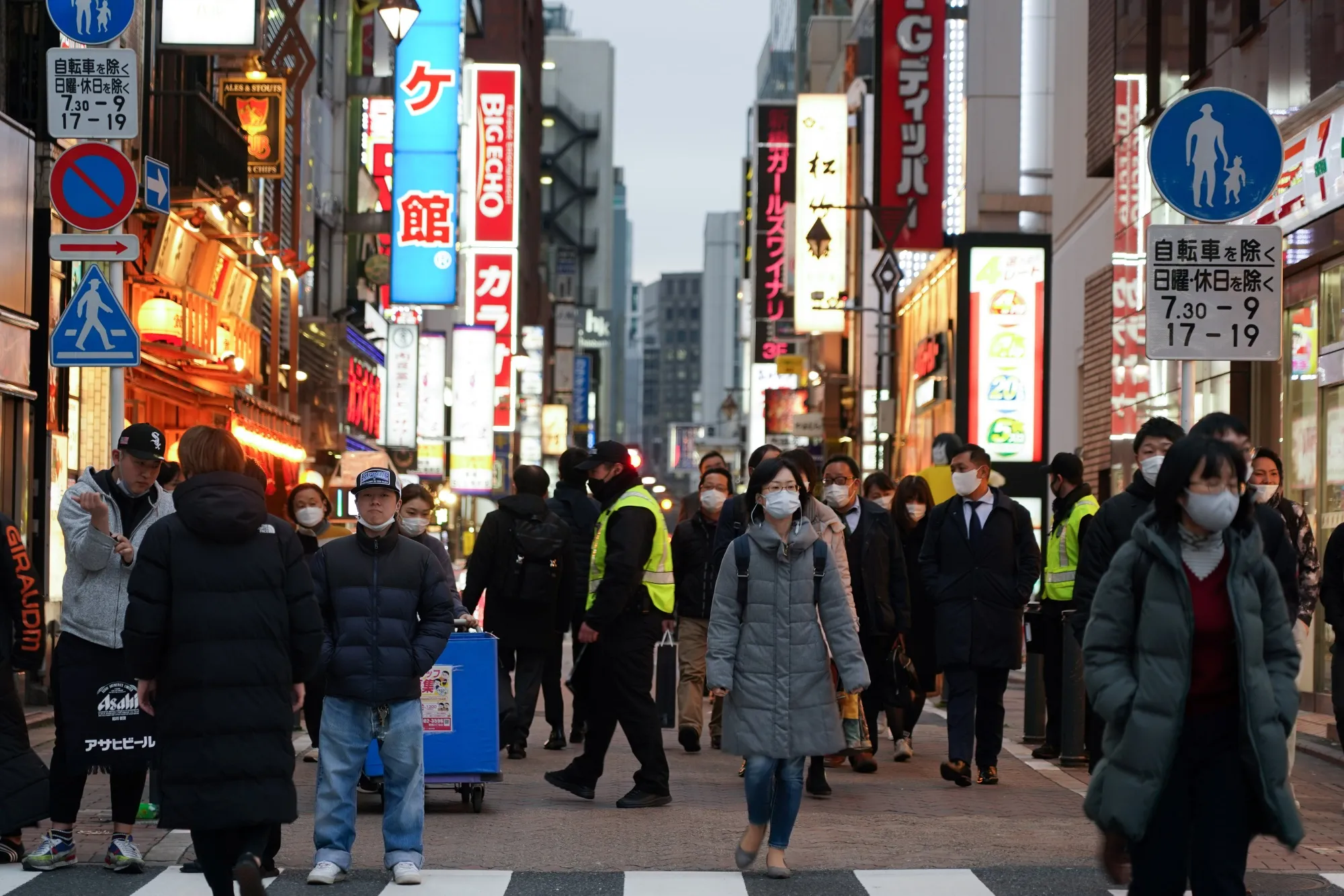Pedestrians wearing protective face masks pass bars and restaurants in the Shimbashi District of Tokyo on&nbsp;March 23.&nbsp;