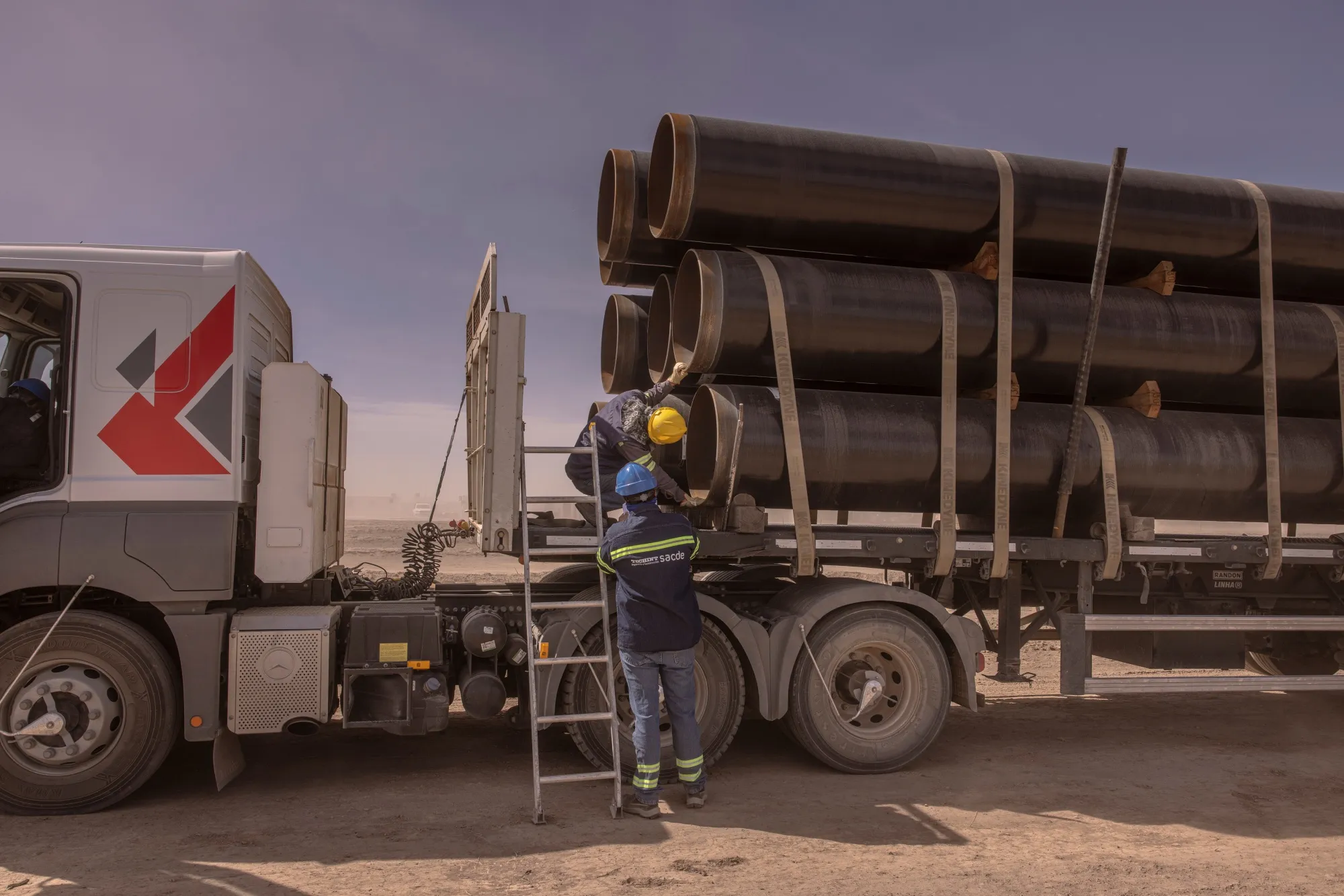 Workers inspect trucks arriving with pipes for the Vaca Muerta Sur pipeline&nbsp;in Neuquen, Argentina.