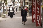 Residents wearing protective face masks walk along a street&nbsp;in the city of Bnei Brak, Israel.