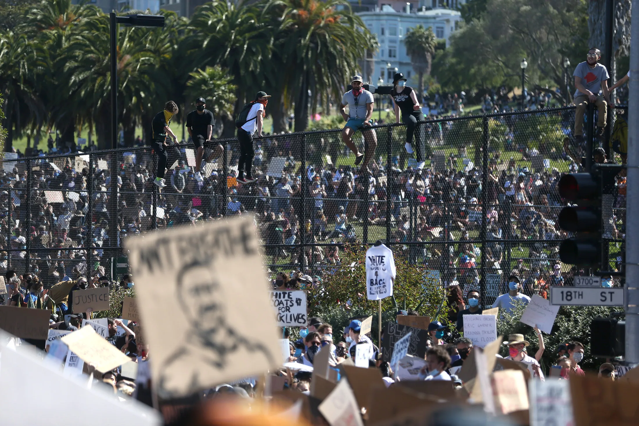 Protesters sit on to of a fence at Dolores Park during a demonstration to honor of George Floyd in San Francisco, California,&nbsp;on June 3.