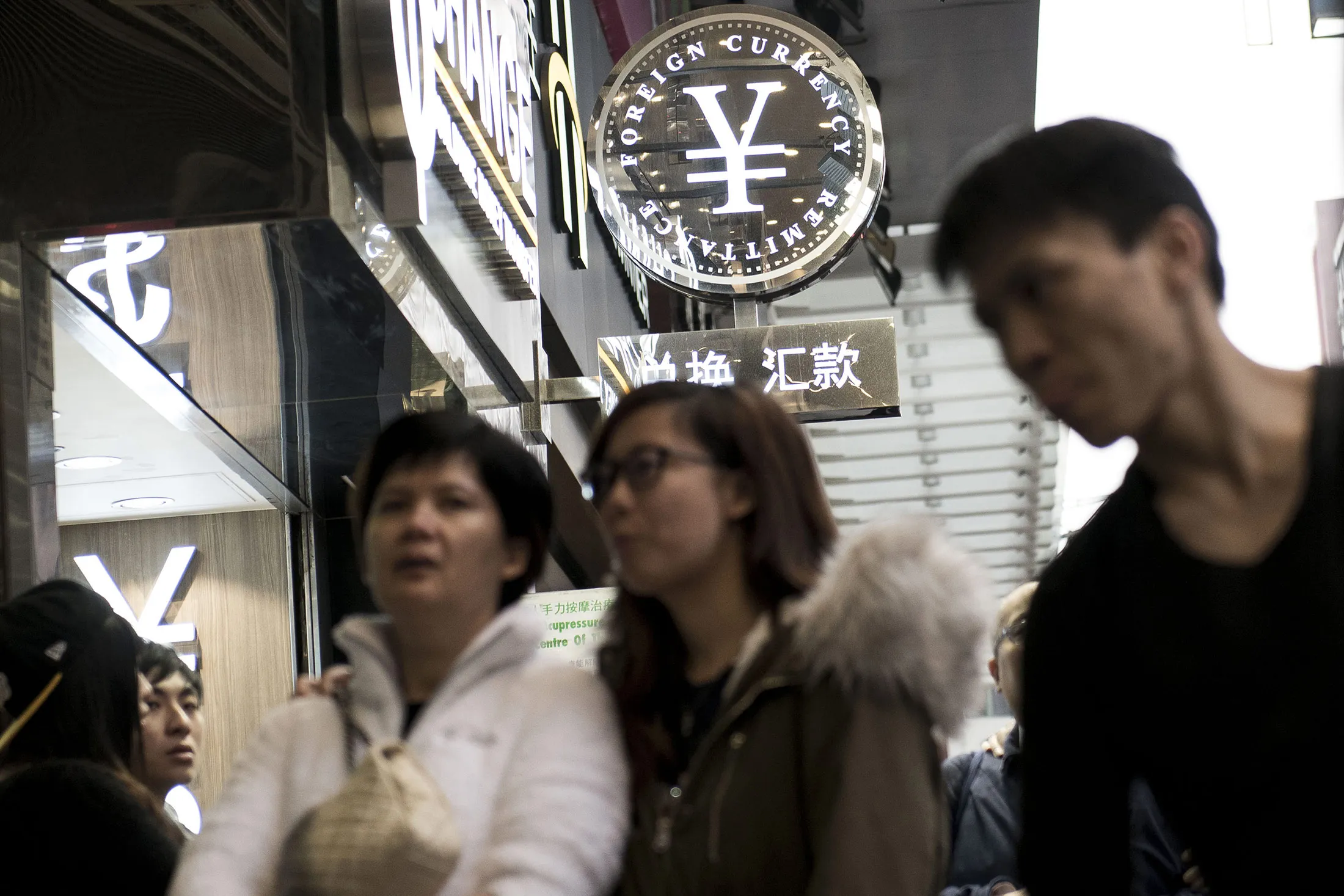 The currency symbol for the Chinese yuan sits on a sign outside a currency exchange store in Hong Kong, China, on Tuesday, Jan. 12, 2016.
