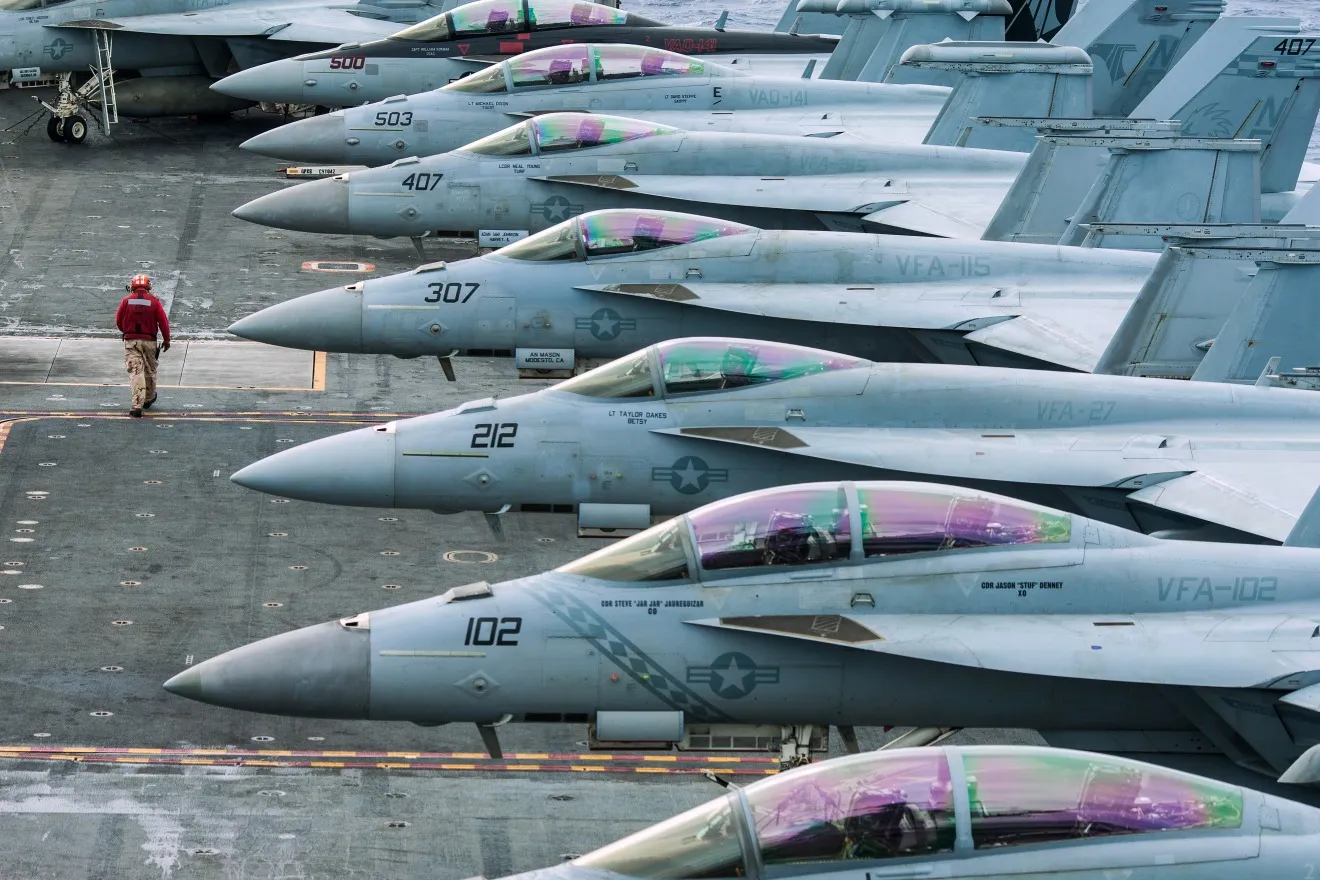 A U.S. Navy technician walks past a row of F/A-18 Super Hornet combat jets, manufactured by Boeing Co., aboard the USS George Washington aircraft carrier near Eastern Samar, the Philippines, on Nov. 20, 2013.