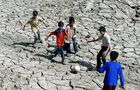 Indian boys play football on a dry bed p
