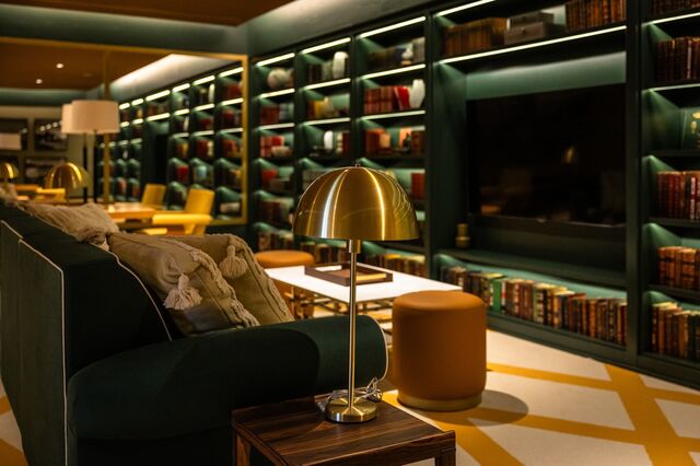 A lounge area with a couch, books, and a flat screen television.