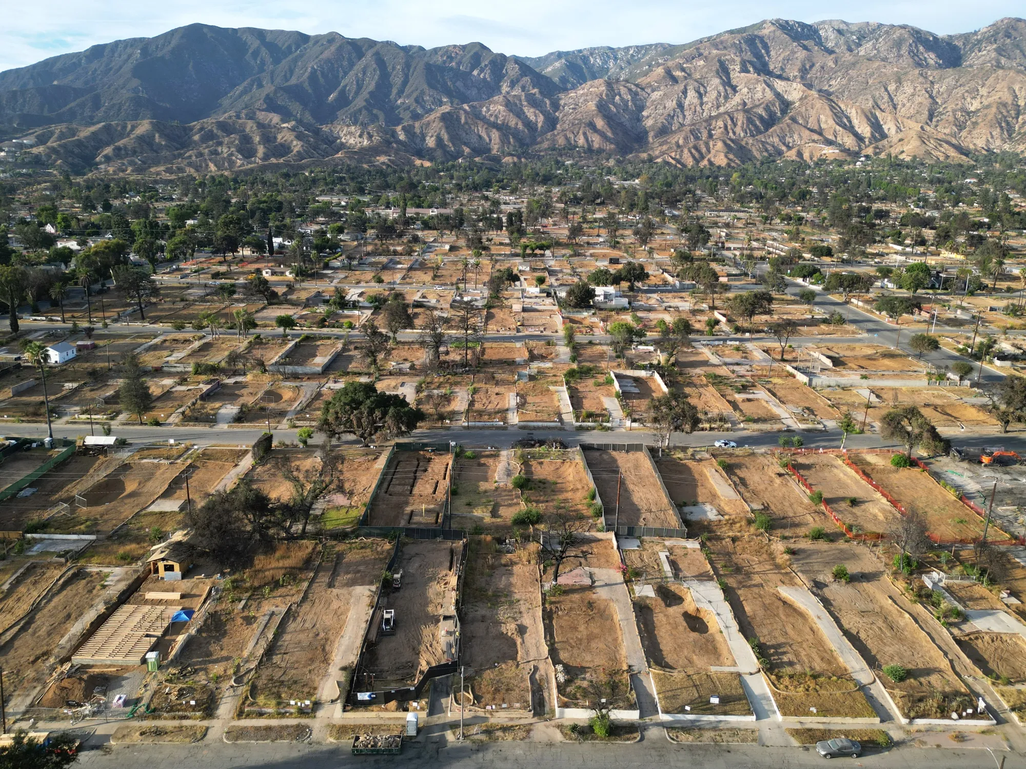 This aerial view shows cleared residential lots, with the San Gabriel Mountains in the background, in Altadena, California on Aug. 21, 2025, just over six months after the Eaton Fire.