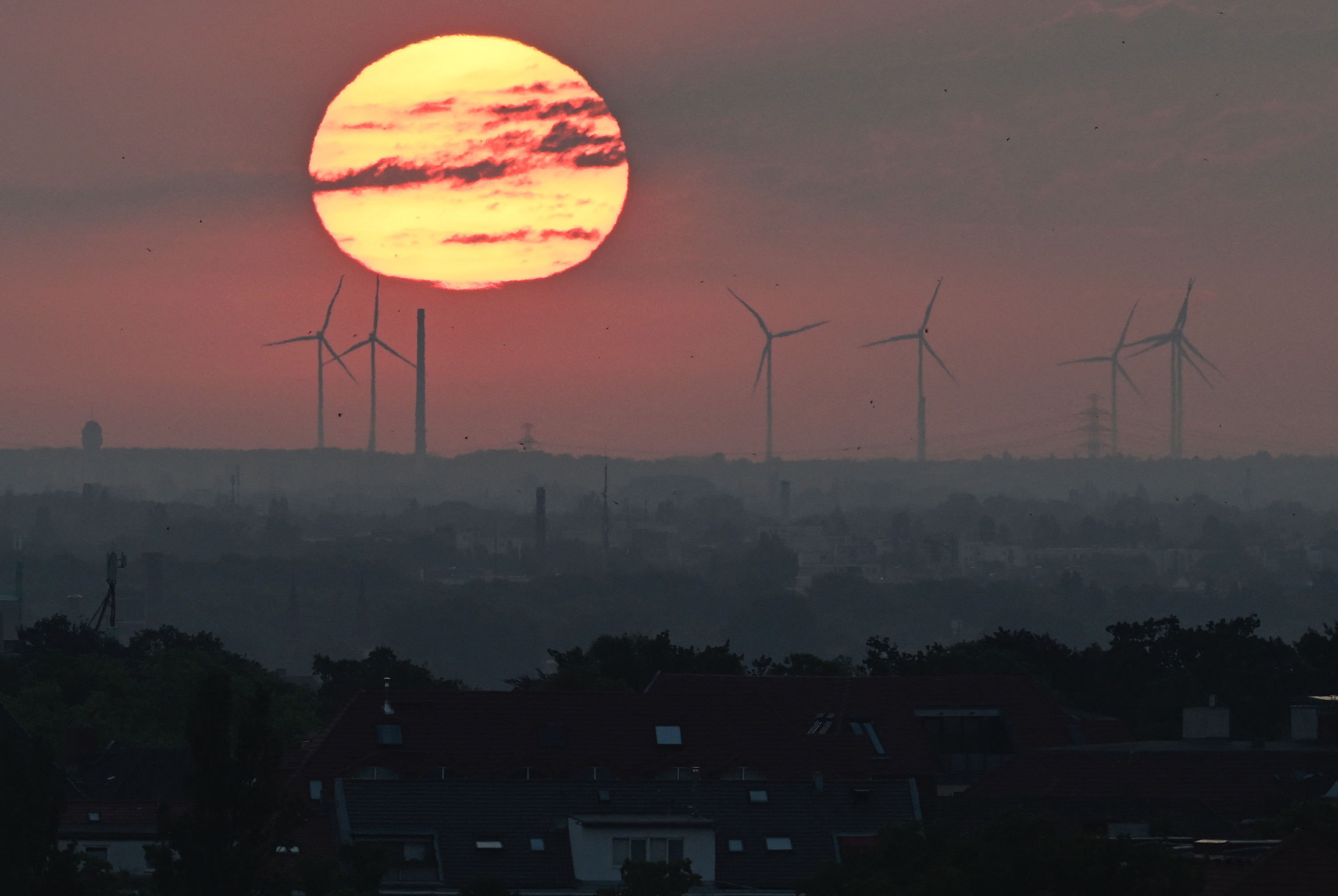 The sun rises beyond wind turbines in Berlin.