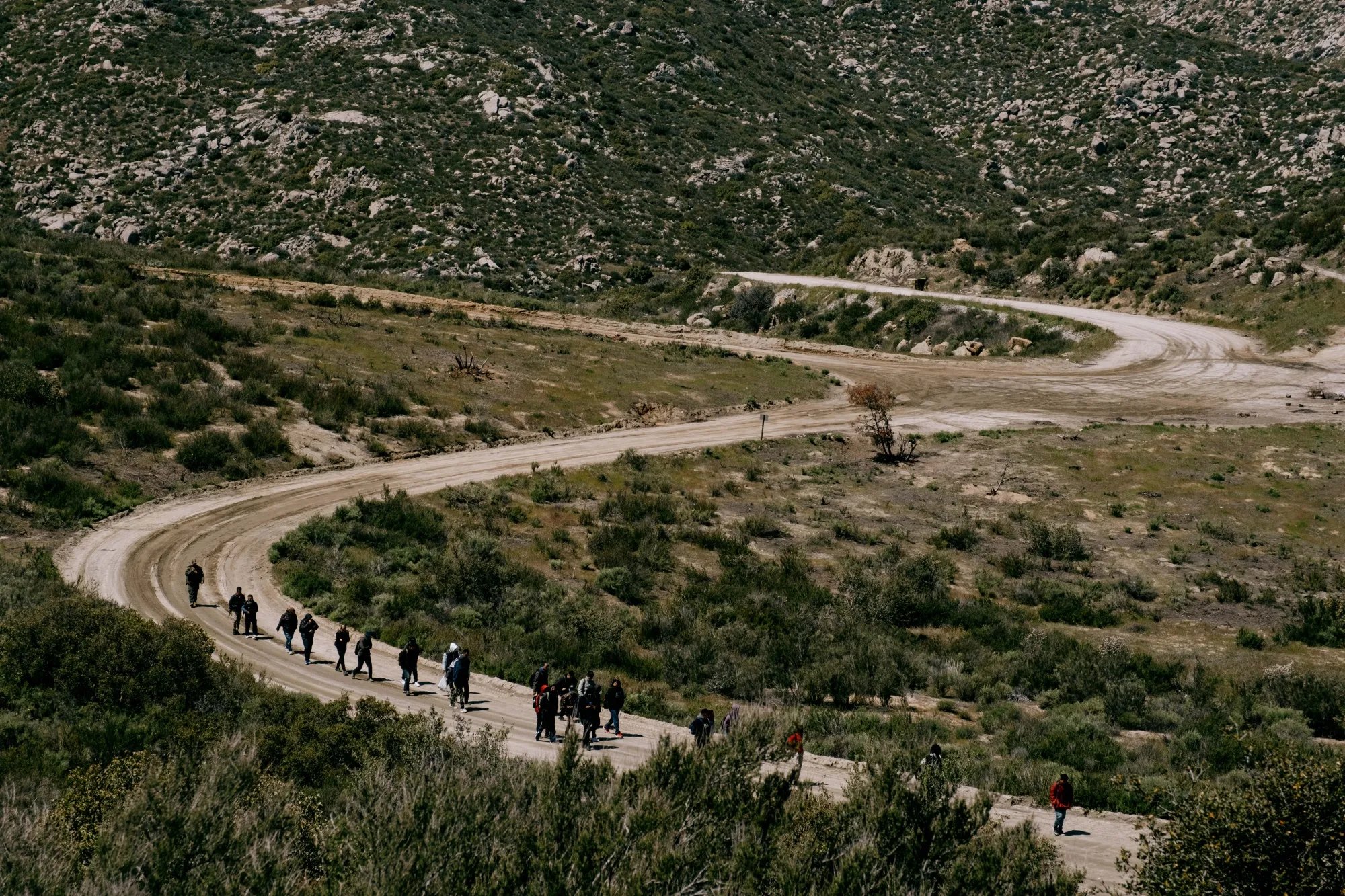 Migrants are led down a mountainous road for processing after crossing the US-Mexico border in Campo, California.