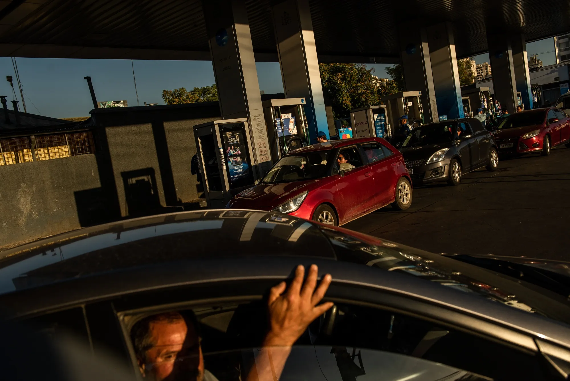 Customers wait in line to fuel up vehicles at a gas station in Santiago on March 24.