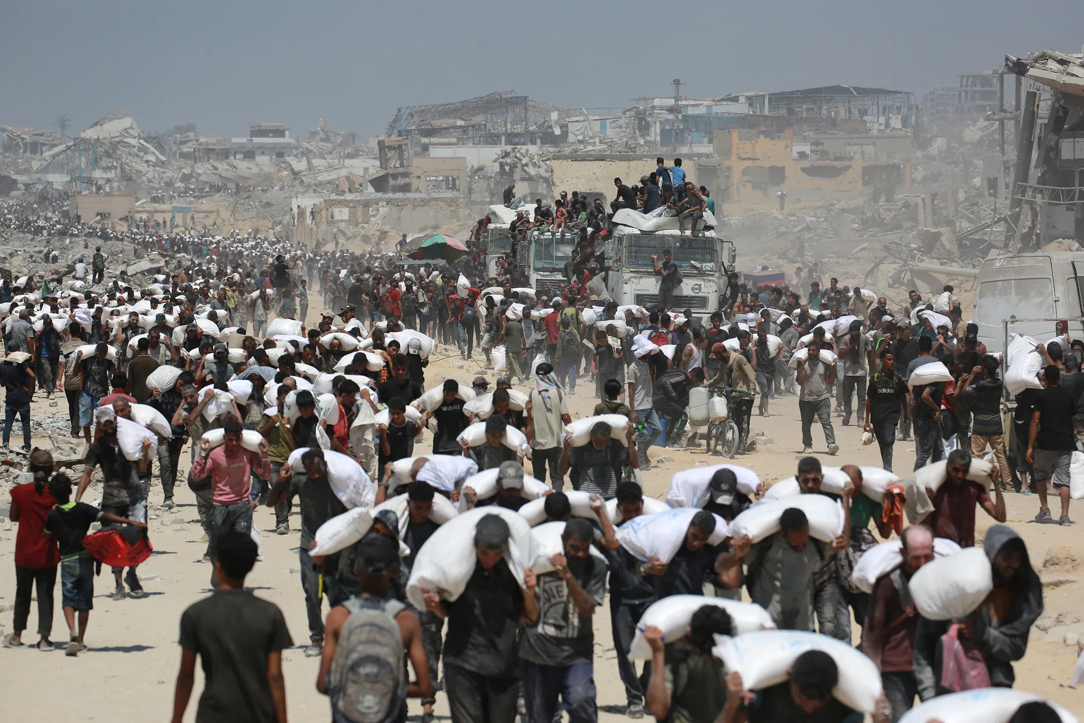 Palestinians walk carrying sacks of flour near Jabalia, in the northern Gaza Strip, on July 27.