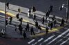 Pedestrians wearing protective face masks wait to cross a road in the Shibuya district of Tokyo, Japan, on Wednesday, Feb. 17, 2021. Bank of Japan Governor Haruhiko Kuroda says it will be hard for the bank to attain its price target even in 2023, hinting at the need to keep monetary easing rolling long after his current term ends.