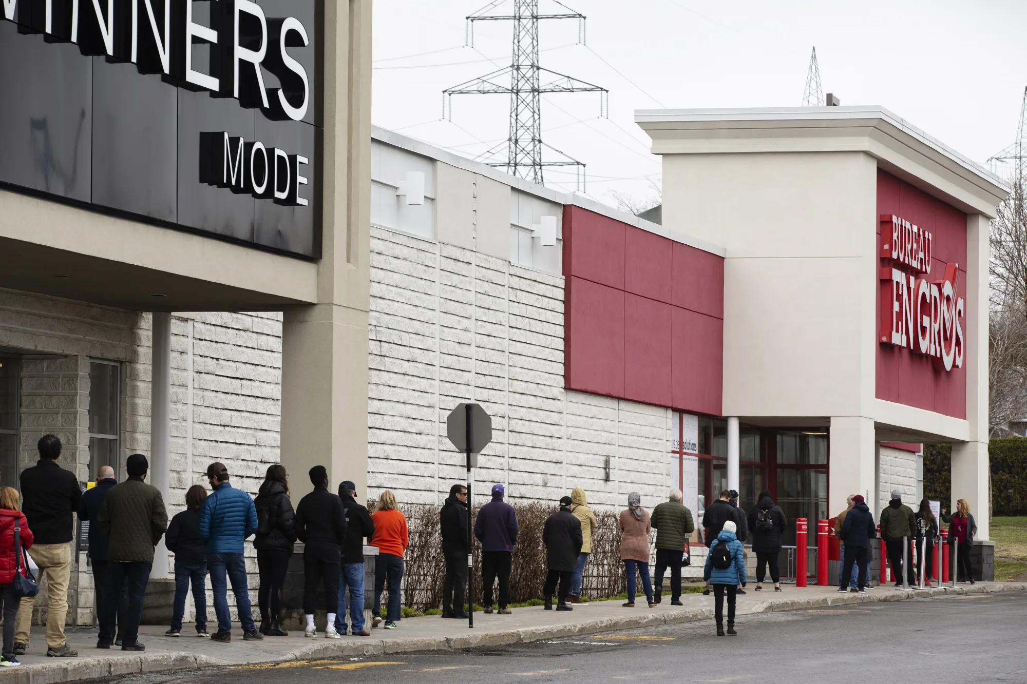 Shoppers wait in line outside a Bureau En Gros store in Quebec City on May 4, 2020.