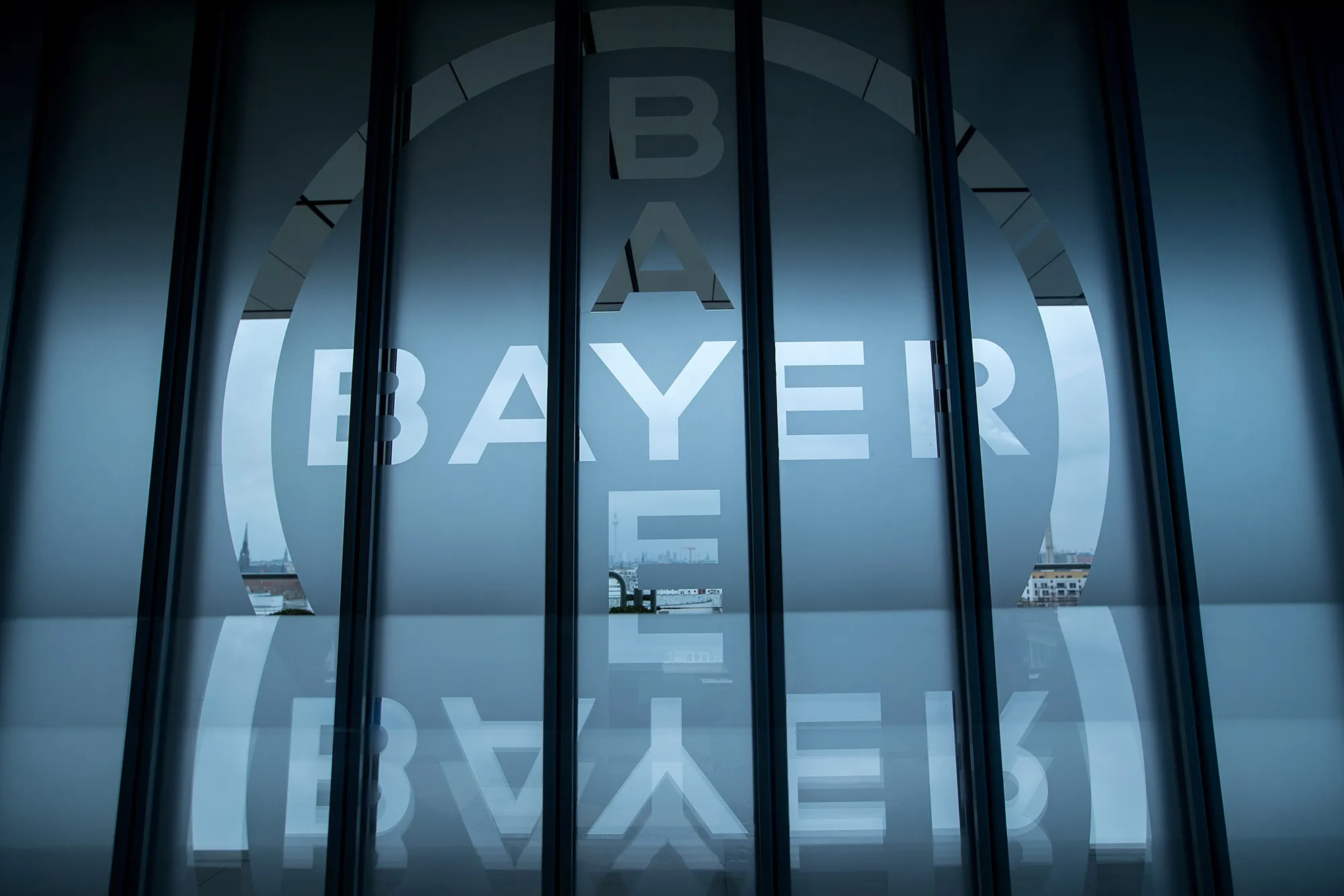 The Bayer AG logo sits on glass panels at the drugmaker's offices in Berlin, Germany, on Friday, Dec. 1, 2017.&nbsp;
