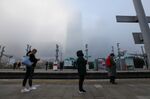 Commuters wearing protective face masks stand at a safe social distance as they wait for a train at Poplar station on the Docklands Light Railwat (DLR) network in London, U.K., on Thursday, Nov. 5, 2020.