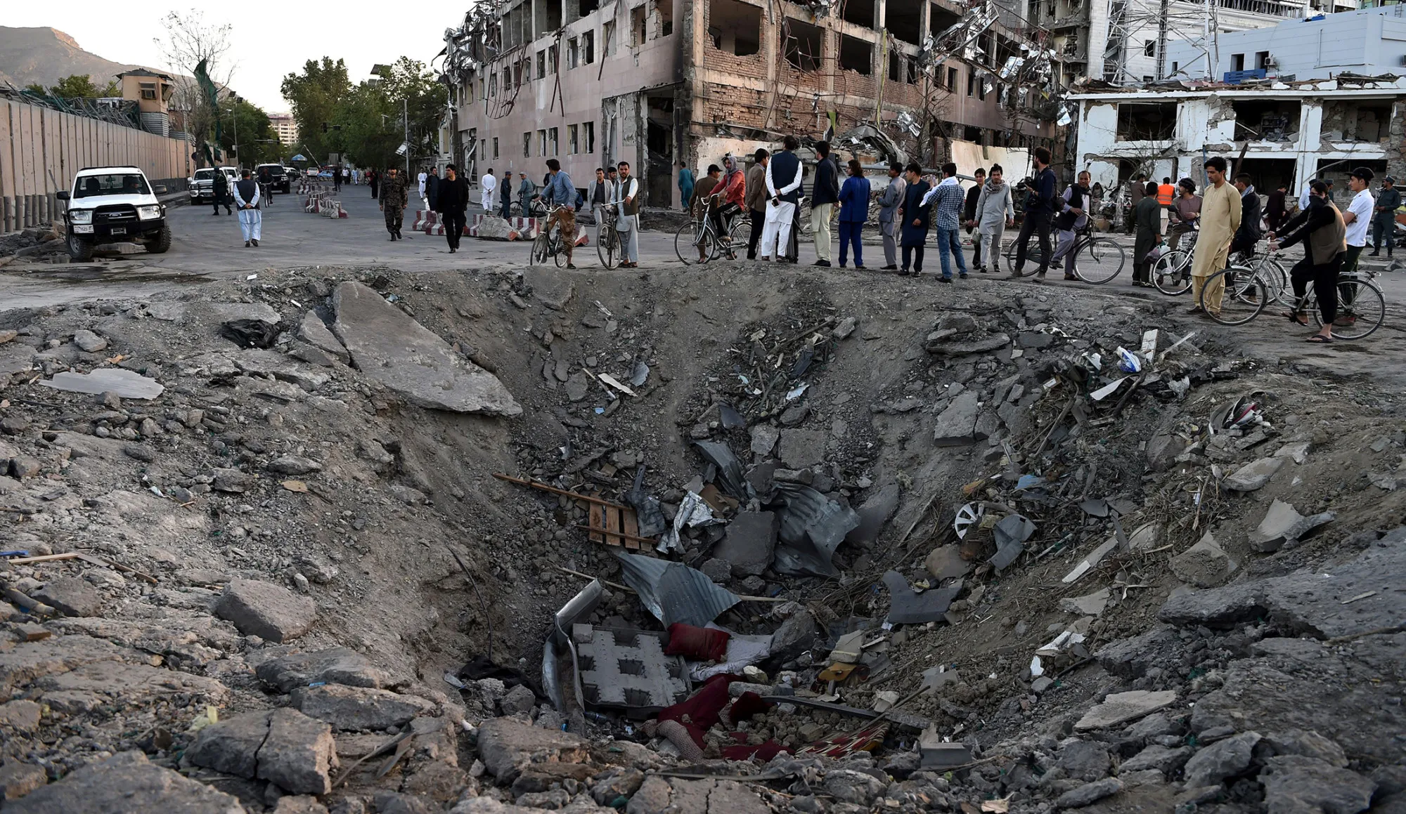 Afghan security forces and residents stand near a&nbsp;crater left by a truck bomb attack in Kabul on May 31, 2017.