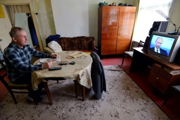 An elderly man watches Vladimir Putin on TV in Stavropol, Russia
