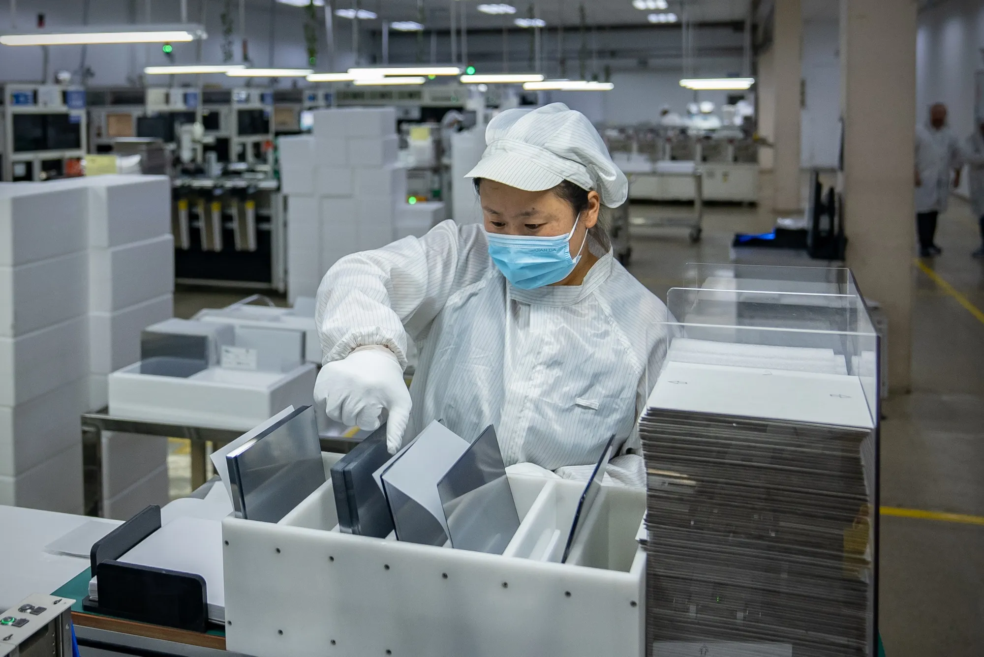 A worker handles wafers at the GCL Technology production plant in Xuzhou, Jiangsu Province, China.