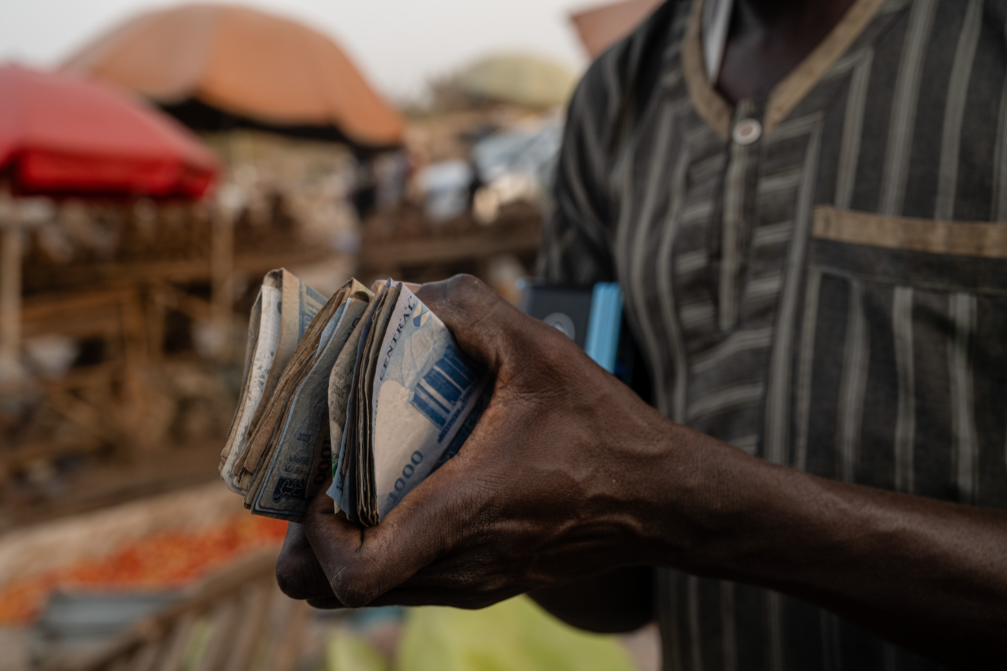 A seller counts Nigerian naira banknotes at a weekly market in Abuja, Nigeria, on Monday, Dec. 8, 2025. Nigeria set an ambitious three-year growth target that leans heavily on the non-oil sector in Africa’s biggest oil-producing nation. Photographer: Etinosa Yvonne/Bloomberg