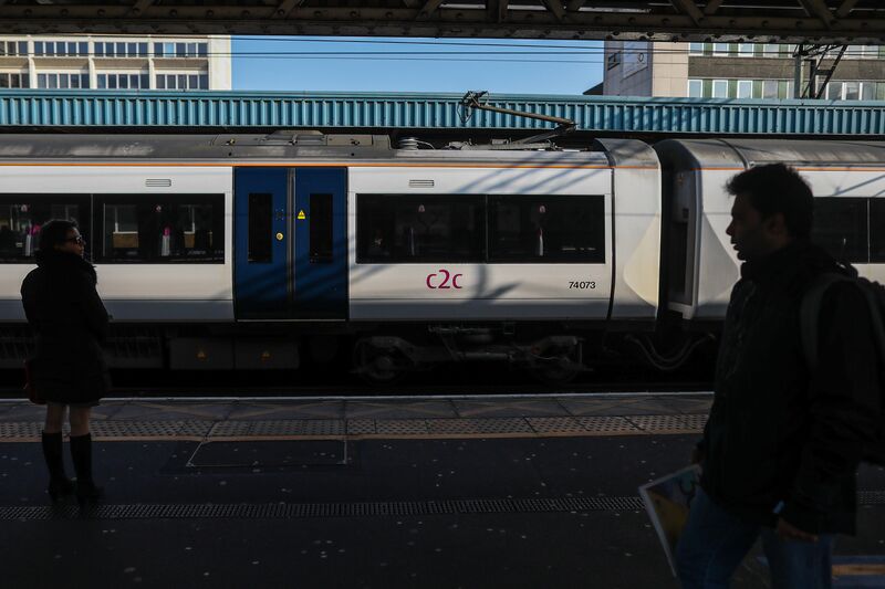 Commuters walk along the platform as a C2C passenger train departs Barking Station. 