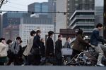 Pedestrians wearing face masks cross a road in the Shinbashi district in Tokyo, Japan, on Monday, March 9, 2020.