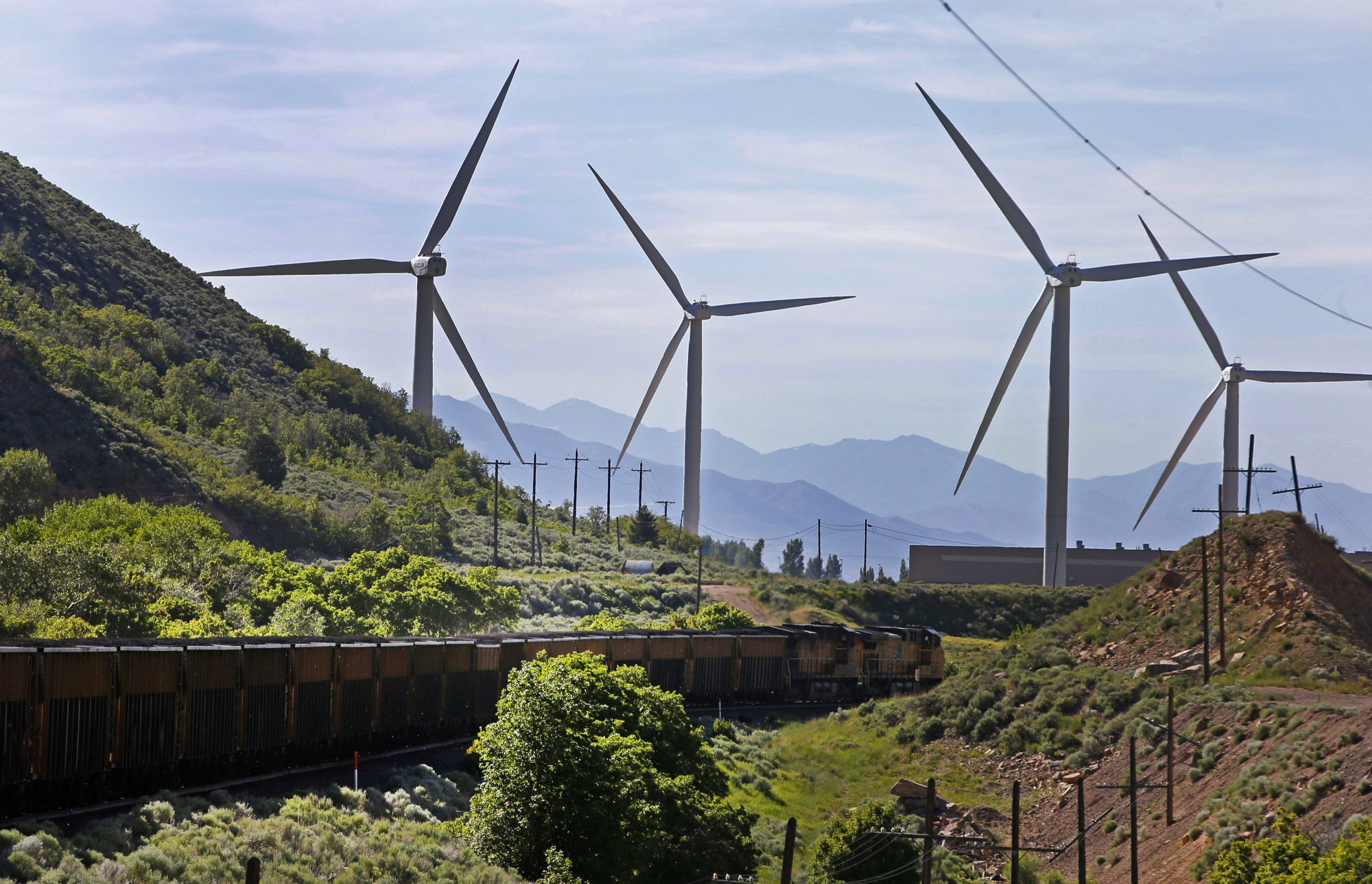 A train transporting coal moves past wind turbines in Spanish Fork, Utah.