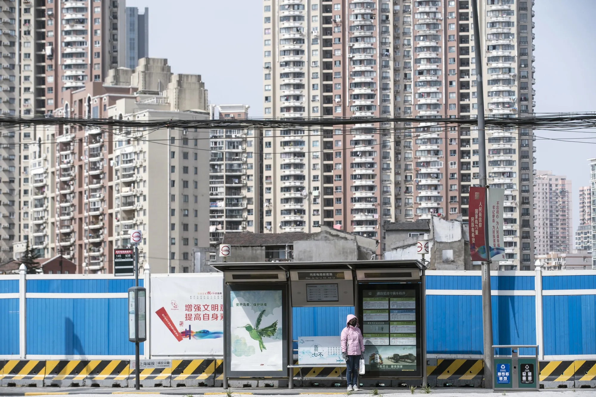 A woman wearing a protective mask stands at a bus stop in Shanghai on Feb. 27.