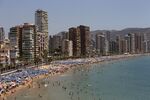 Apartment blocks stand behind a beach packed with holidaymakers in Benidorm.