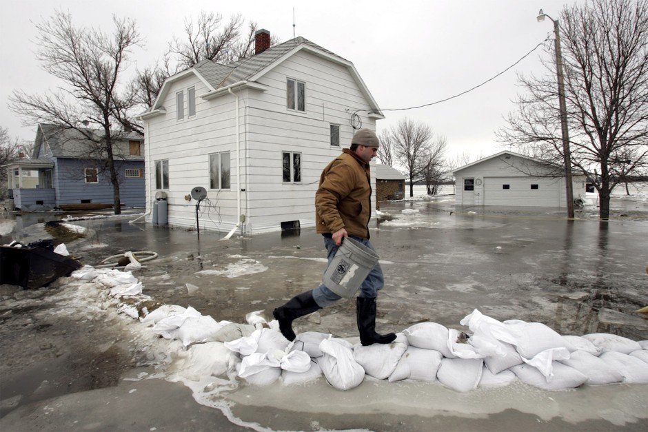 Justin Thompson walks on a sandbag dike as he carries a bucket of water to prime a pump and attempt to drain the water around his uncle's house south of Fargo, March 29, 2009. Experts say that taking practical steps, even small ones, before or during a disaster has psychological benefits.