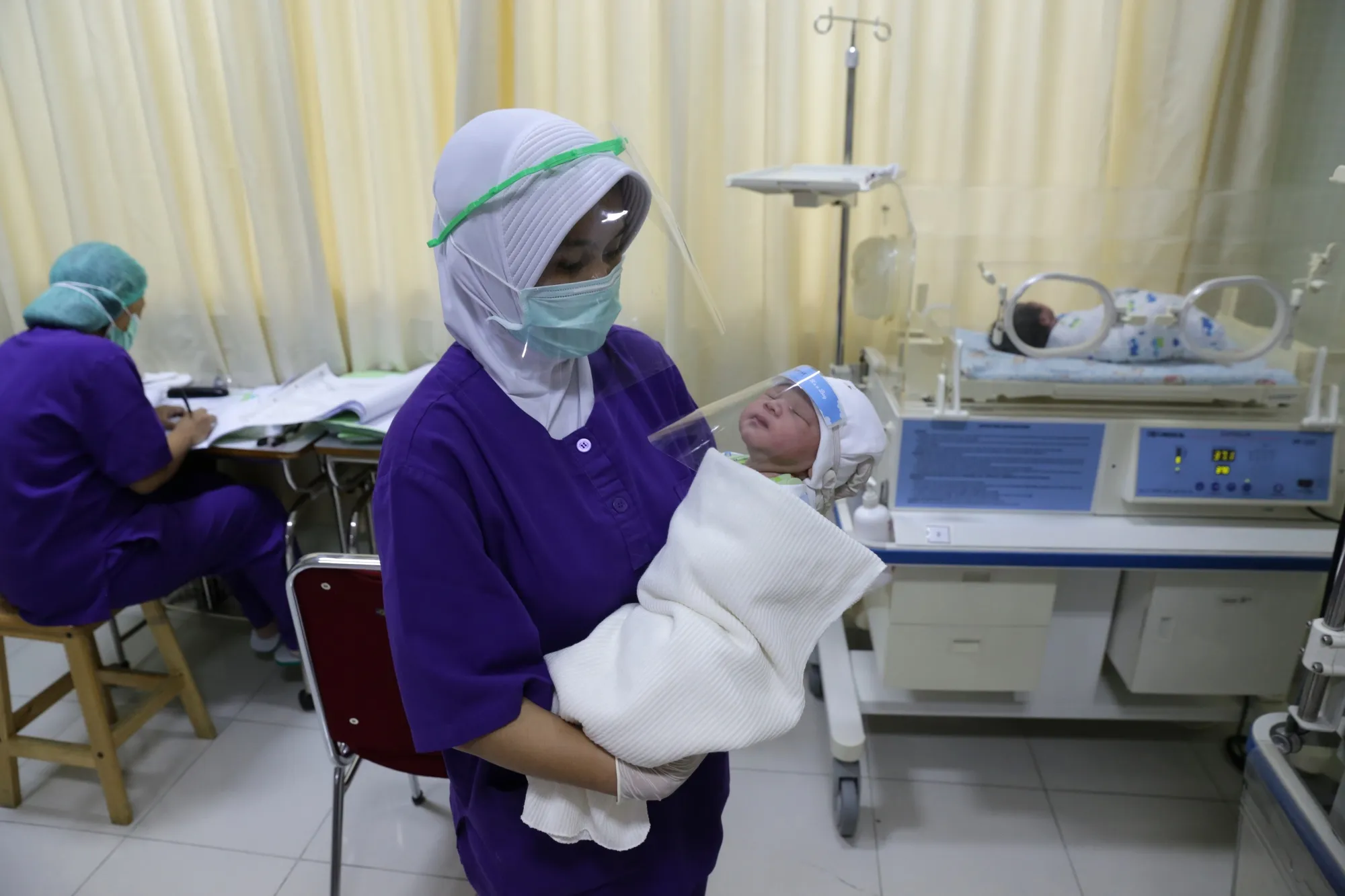 A nurse holds a newborn baby wearing face shield to protect against Covid-19 in Jakarta, in April 2020.
