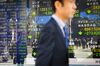 A man passes in front of an electronic stock board outside a securities firm in Tokyo, Japan, on Tuesday, Feb. 6, 2018. Japan's broad Topix index and blue-chip Nikkei 225 Stock Average were poised to enter a correction as the nation's shares headed for the biggest decline since June 2016, following U.S. peers lower amid rising concern that inflation will force interest rates higher.