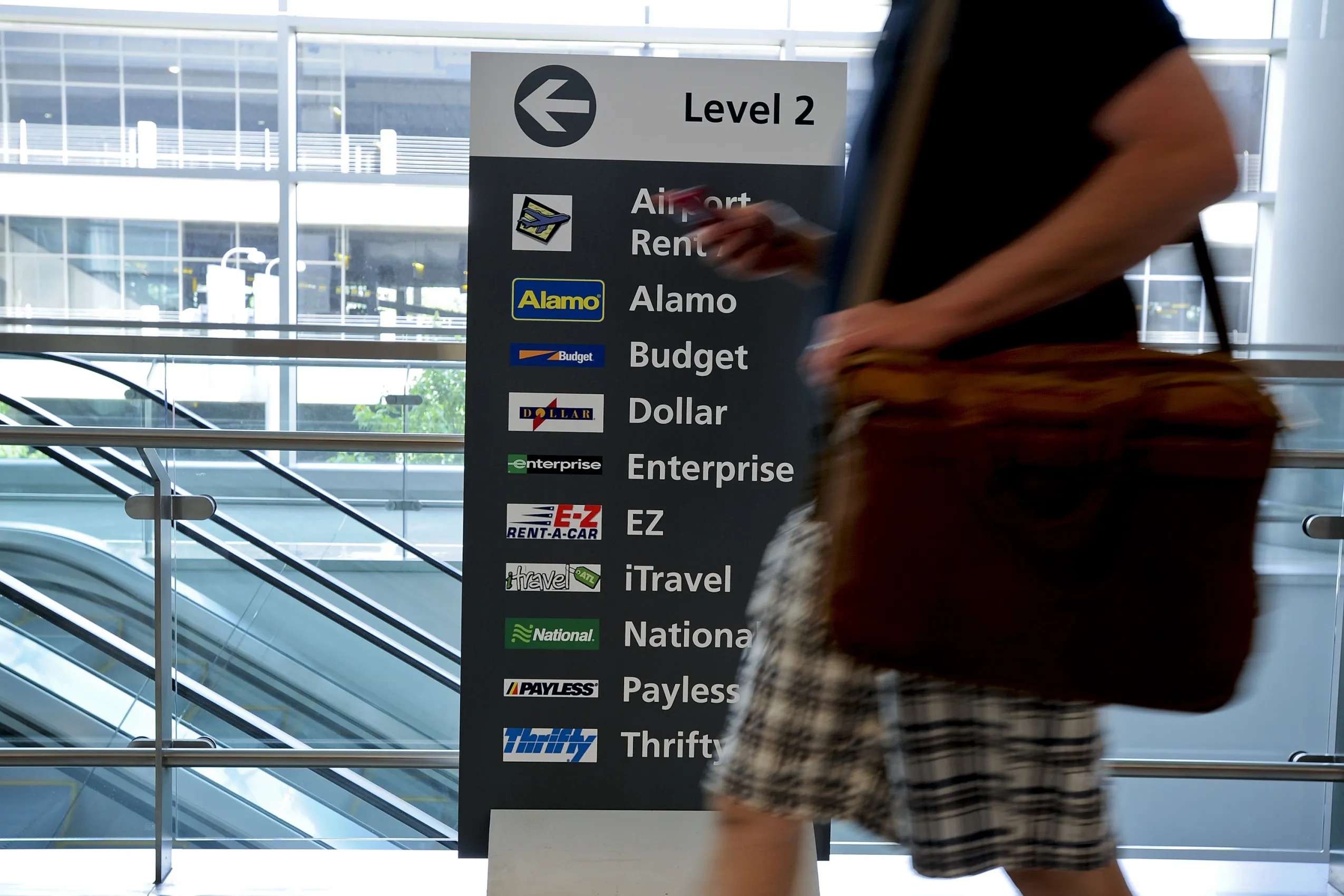 A traveler walks past a sign displaying the various car-rental companies at Hartsfield-Jackson Atlanta International Airport in Atlanta, Georgia.
