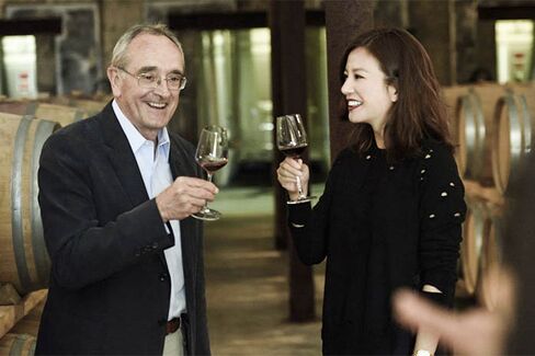 Famous wine consultant Jean-Claude Berrouet, who made Chateau Petrus for 47 years, shares a glass of red with film star Zhao Wei in the barrel room at Chateau Monlot. Wei purchased the chateau in 2011.