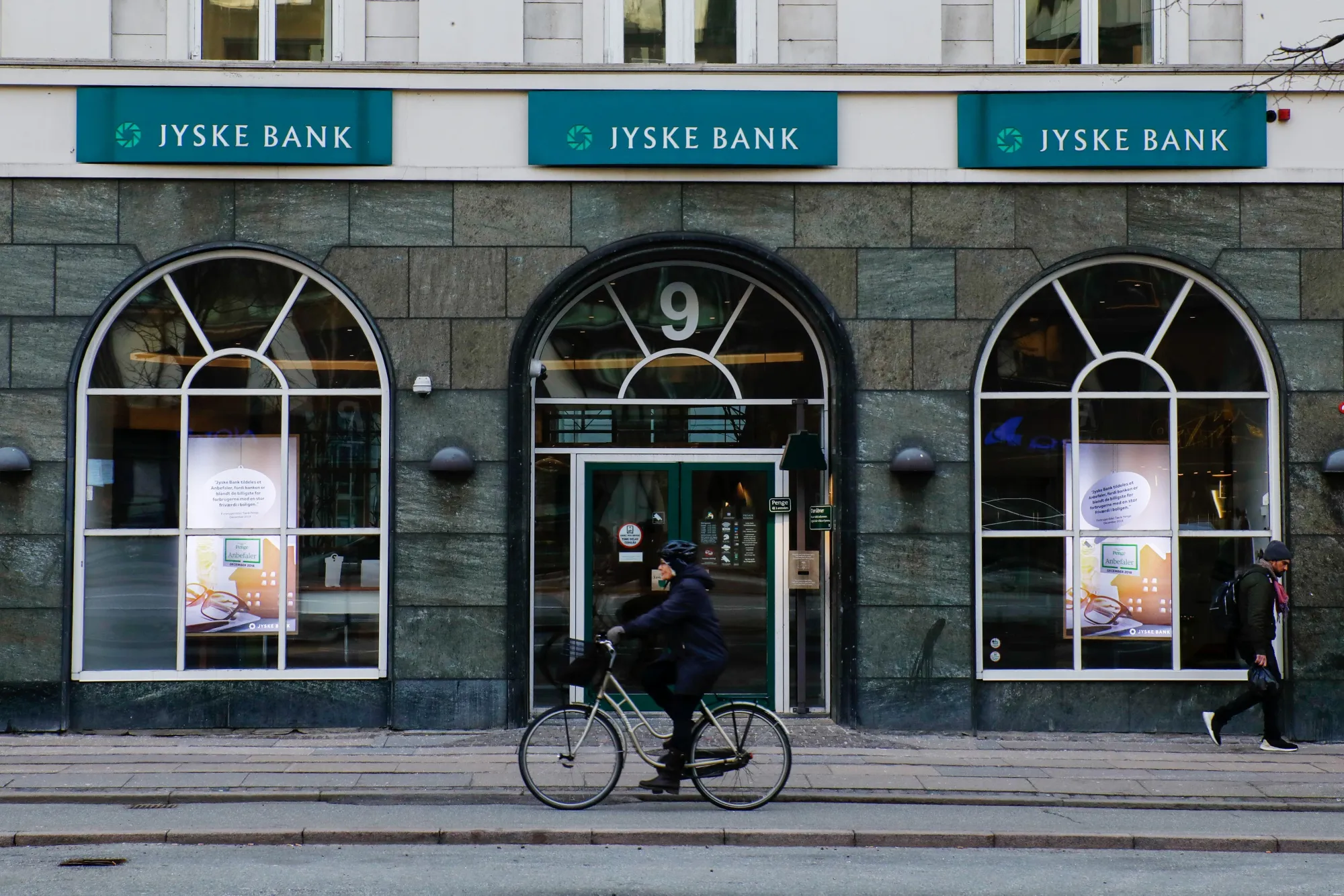 A cyclist passes a Jyske Bank A/S bank branch in Copenhagen.