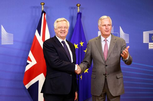 握手を交わすデービス英EU離脱担当相(左)とEU側交渉責任者のバルニエ氏(7月17日、ブリュッセル)