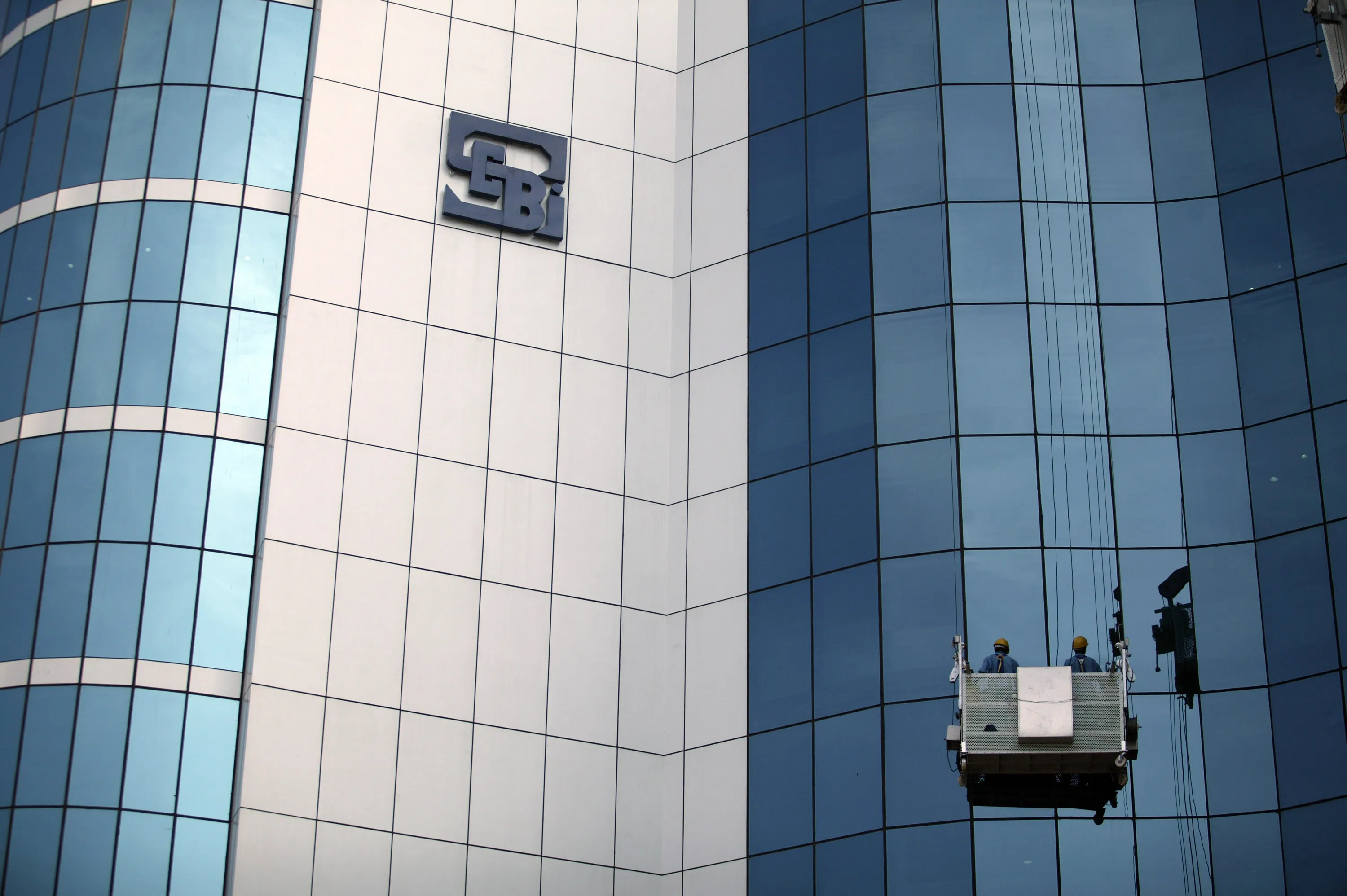 A worker cleans the glass of the Securities &amp; Exchange Board of India in Mumbai.
