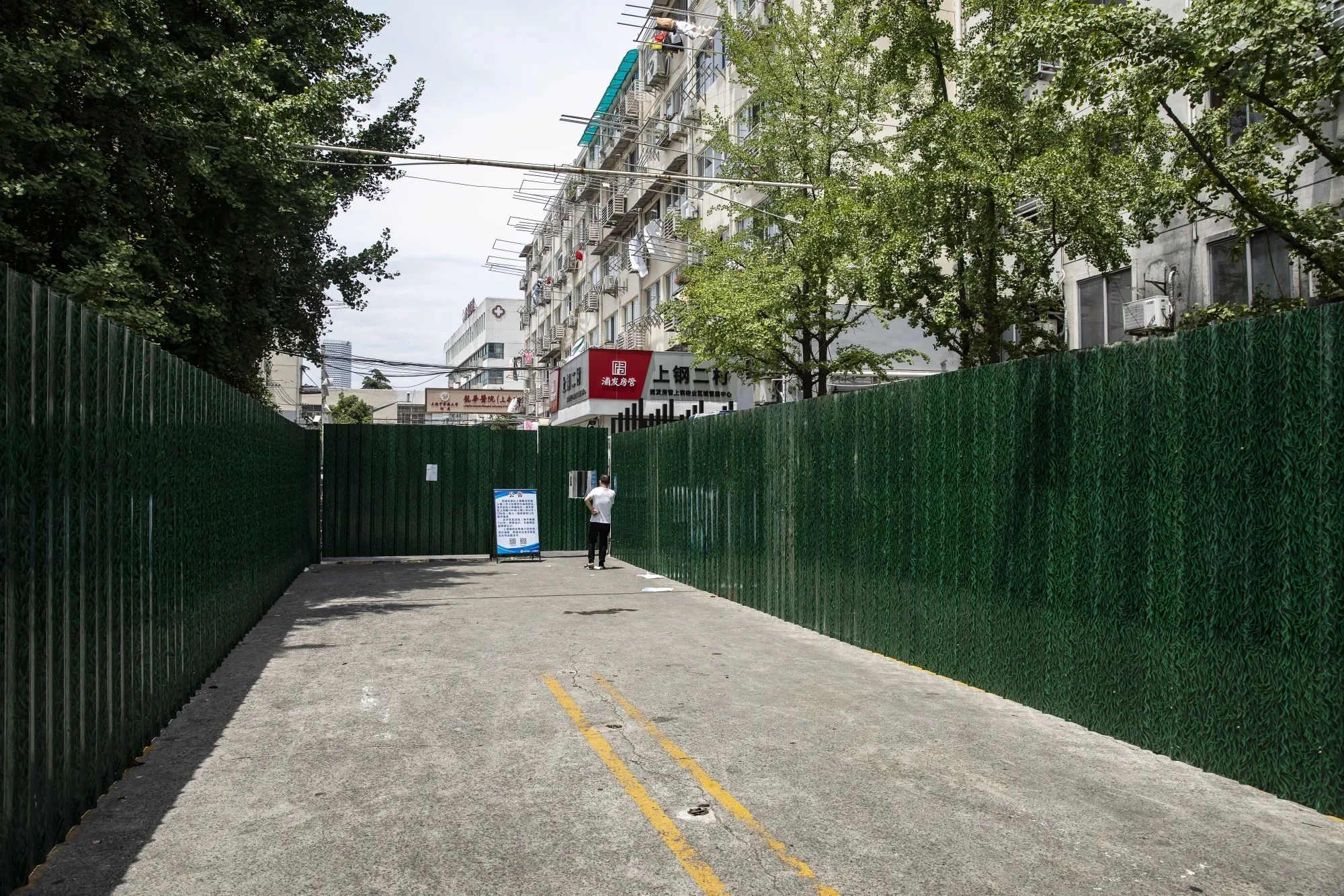 A pedestrian in front of fencing surrounding a residential neighborhood placed under lockdown due to Covid-19 in Shanghai on July 6.