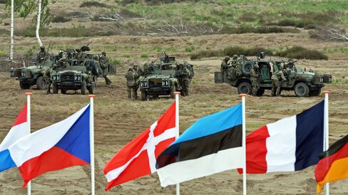 Soldiers prepare for a NATO Response Force (NRF) exercise behind flags of participating nations in Zagan, southwest Poland on June 18, 2015.