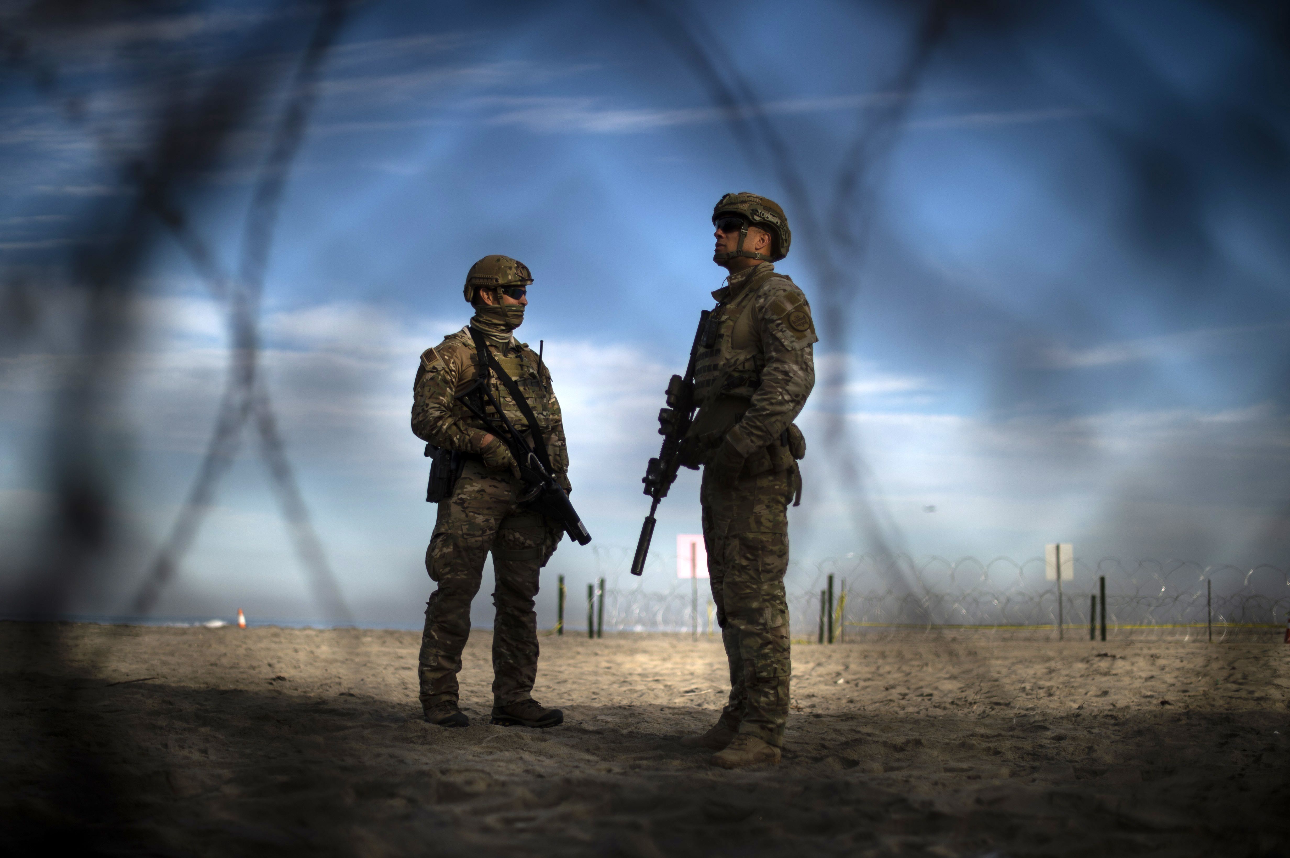 US Customs and Border Protection agents stand guard on the US side of the US-Mexico border fence.