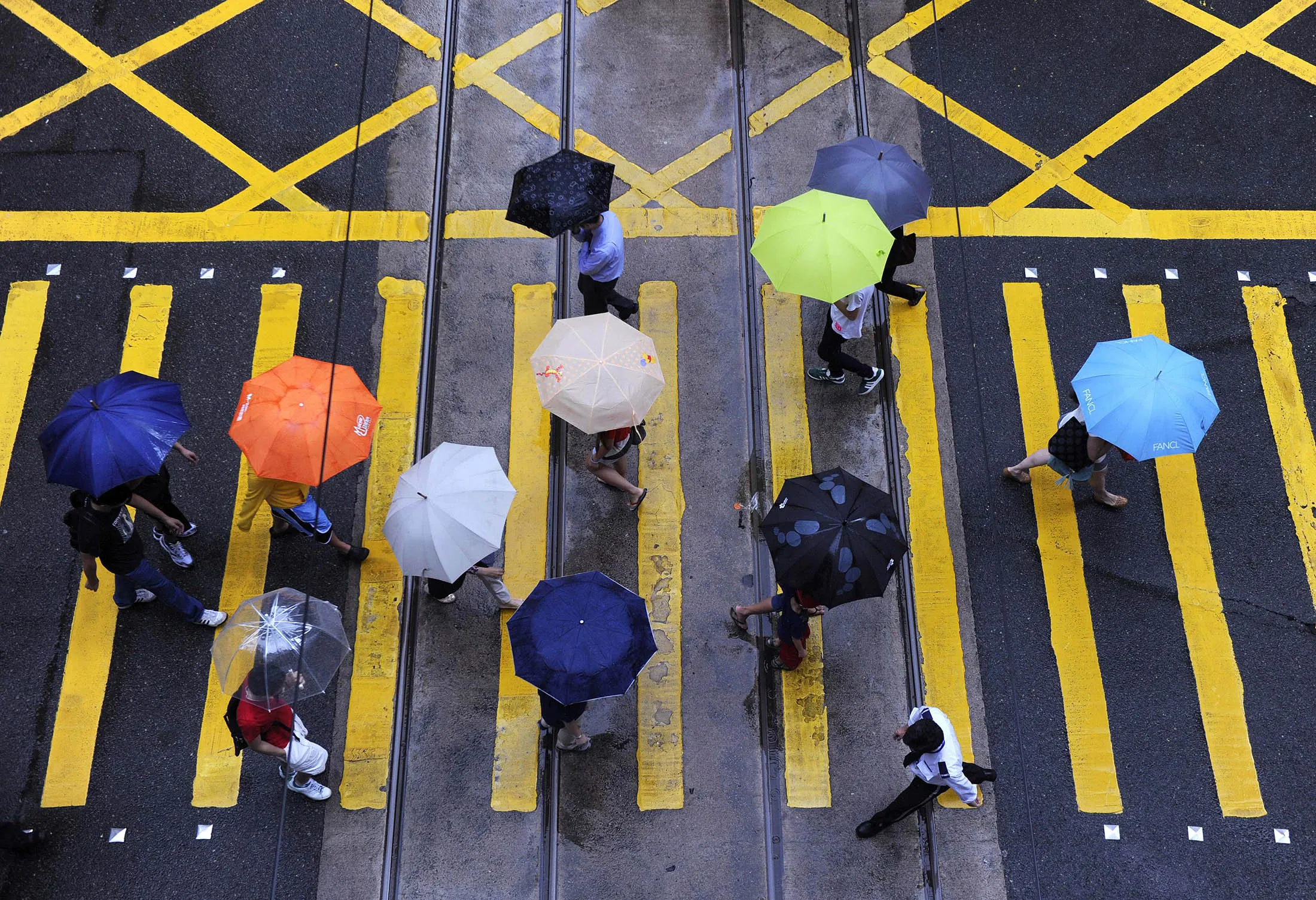 Pedestrians cross an intersection as rain falls over Hong Kong on July 25, 2013. Rain continued as a broad trough of low pressure brought unsettled weather to the northern part of the South China Sea and the coast of Guangdong, the Hong Kong weather observatory reported. AFP PHOTO / Dale de la Rey (Photo credit should read DALE de la REY/AFP/Getty Images)
