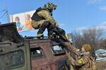 A Ukrainian Territorial Defence fighter takes the automatic grenade launcher from a destroyed Russian infantry mobility vehicle&nbsp;in Kharkiv on Feb.&nbsp;27, 2022.