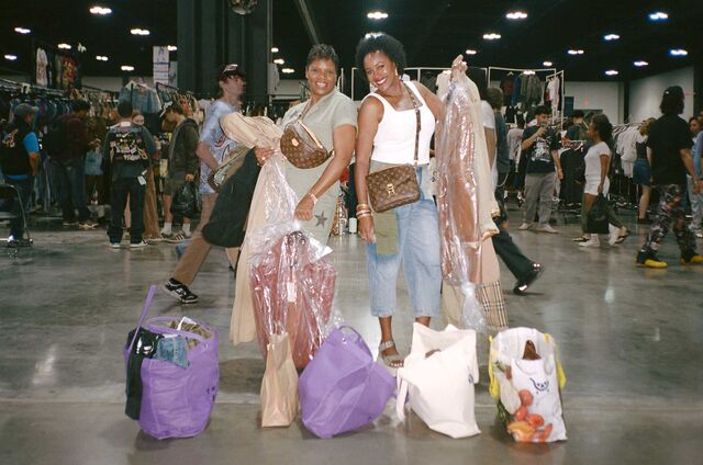Two women stand with clothing they've purchased at ThriftCon