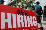 A man walks past a "now hiring" sign posted outside of a restaurant in Arlington, Virginia.