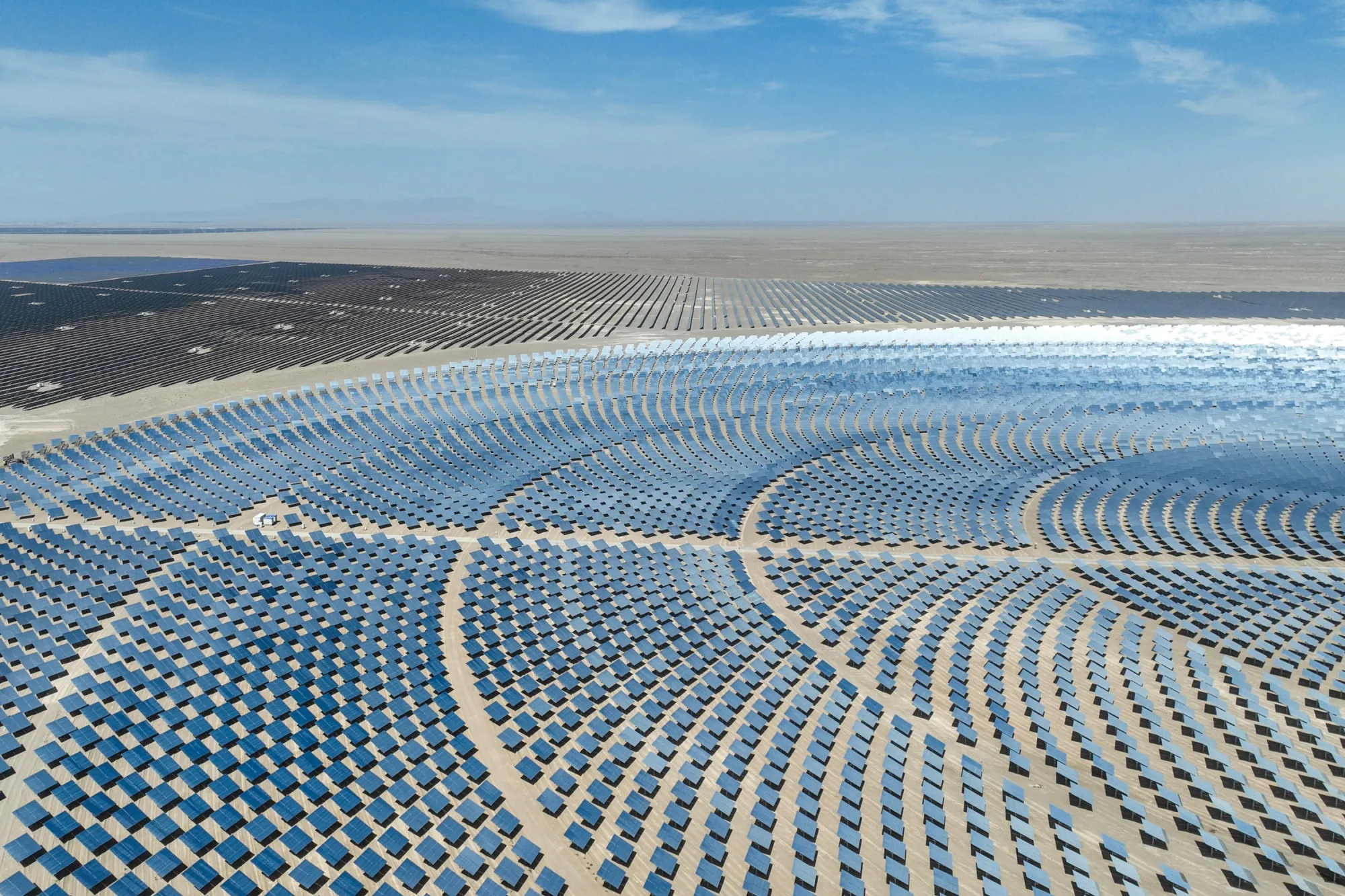 Aerial image showing thousands of solar panels arranged in a radial pattern within the Gobi Desert landscape, Jiuquan, Gansu province, China, June 2026