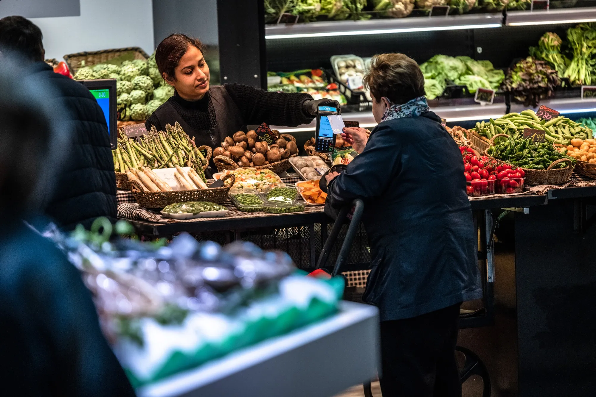 A customer pays with a contactless card at a fresh produce stall in Barcelona.