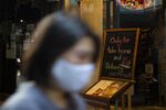 A pedestrian wearing a protective face mask passes a restaurant offering take-away and food delivery services only due to coronavirus lockdown measures in Bangkok, on March 30.