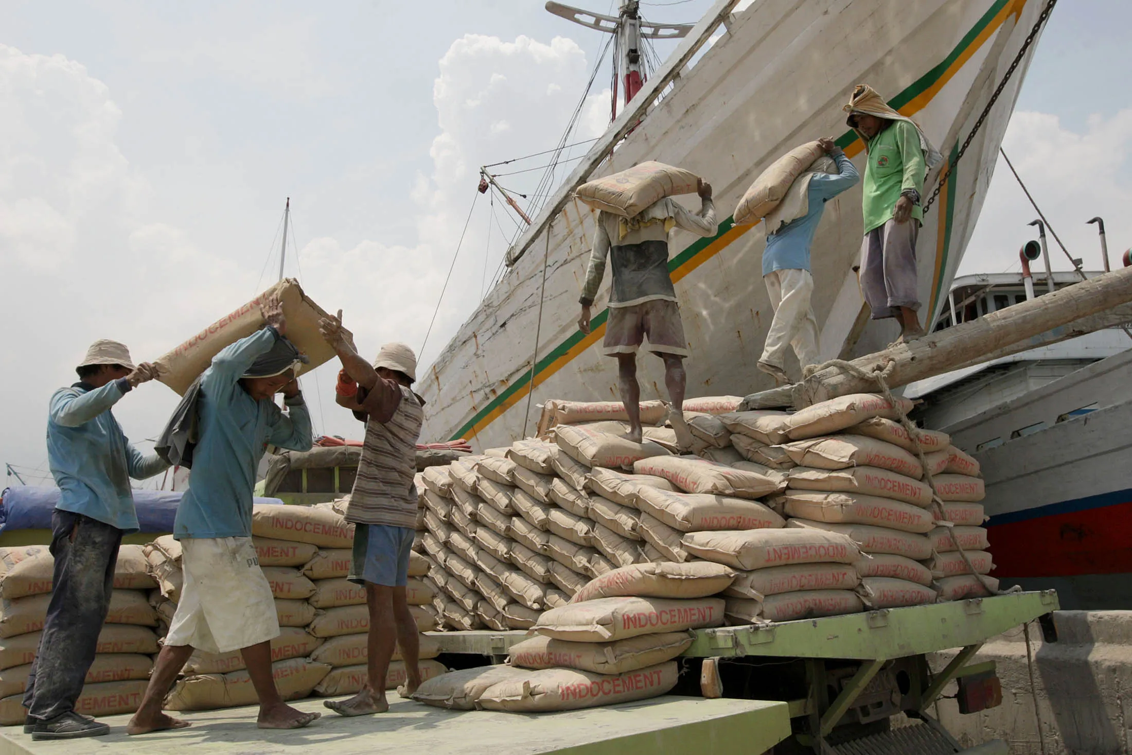 Workers move bags of cement into a ship in Jakarta.
