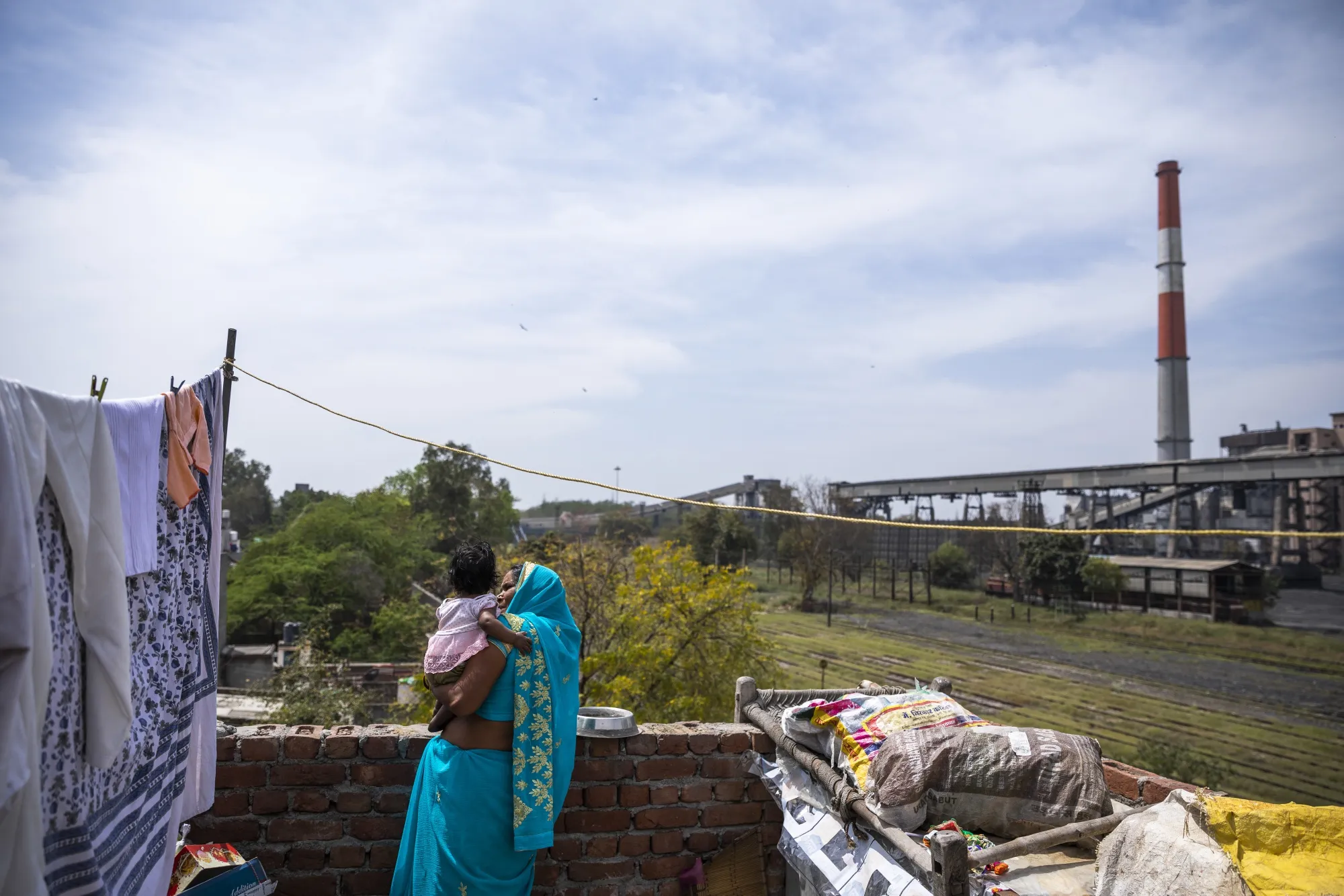 A woman holds her granddaughter on a terrace overlooking the now shut coal-fired NTPC Ltd. Badarpur Thermal Power Station in Badarpur, Delhi.
