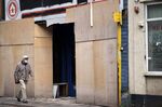 A man walks past a boarded up shop in in Stoke-on-Trent, UK.