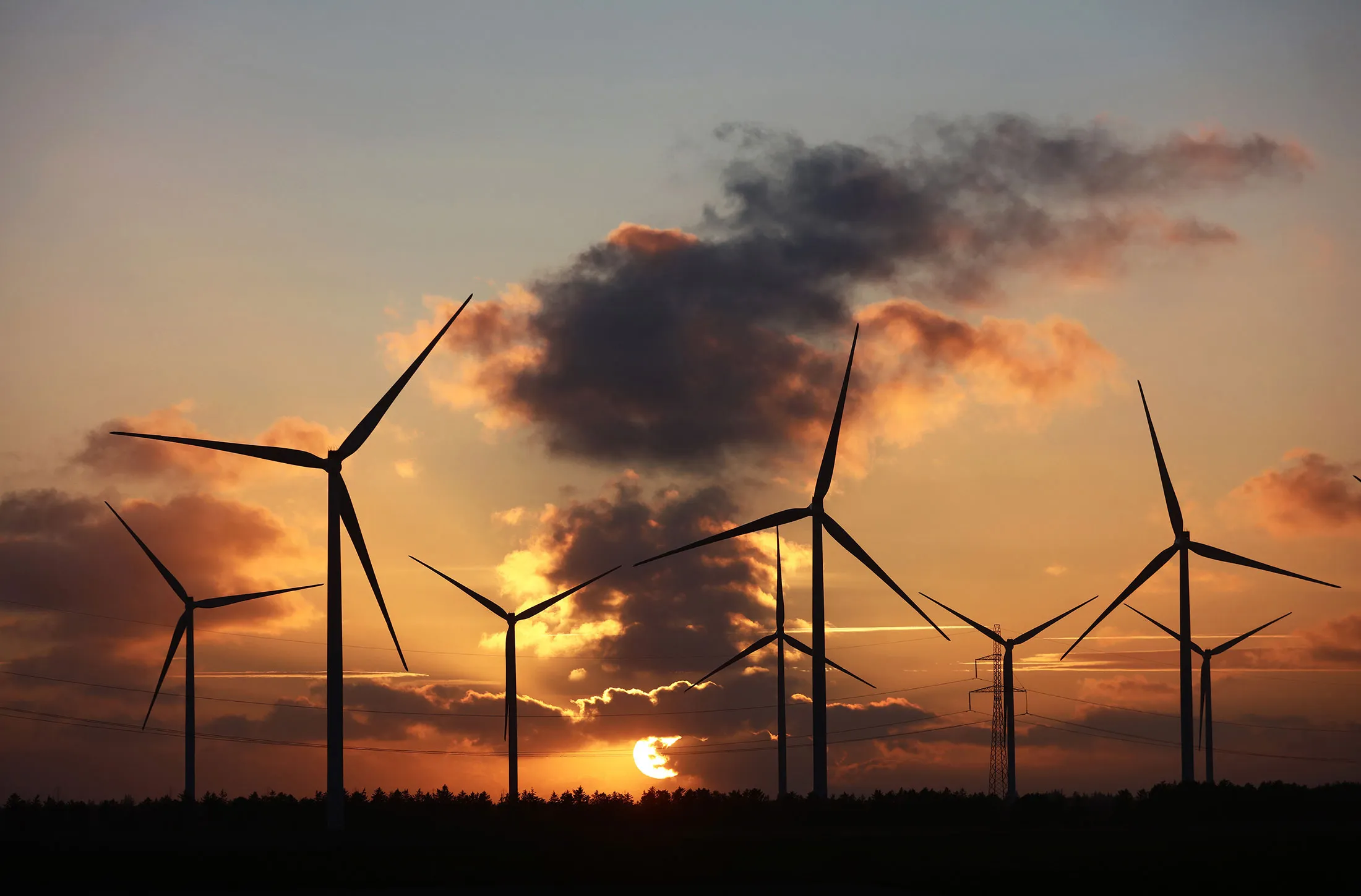 The sun sets beyond wind turbines near Fjerritslev, Denmark.
